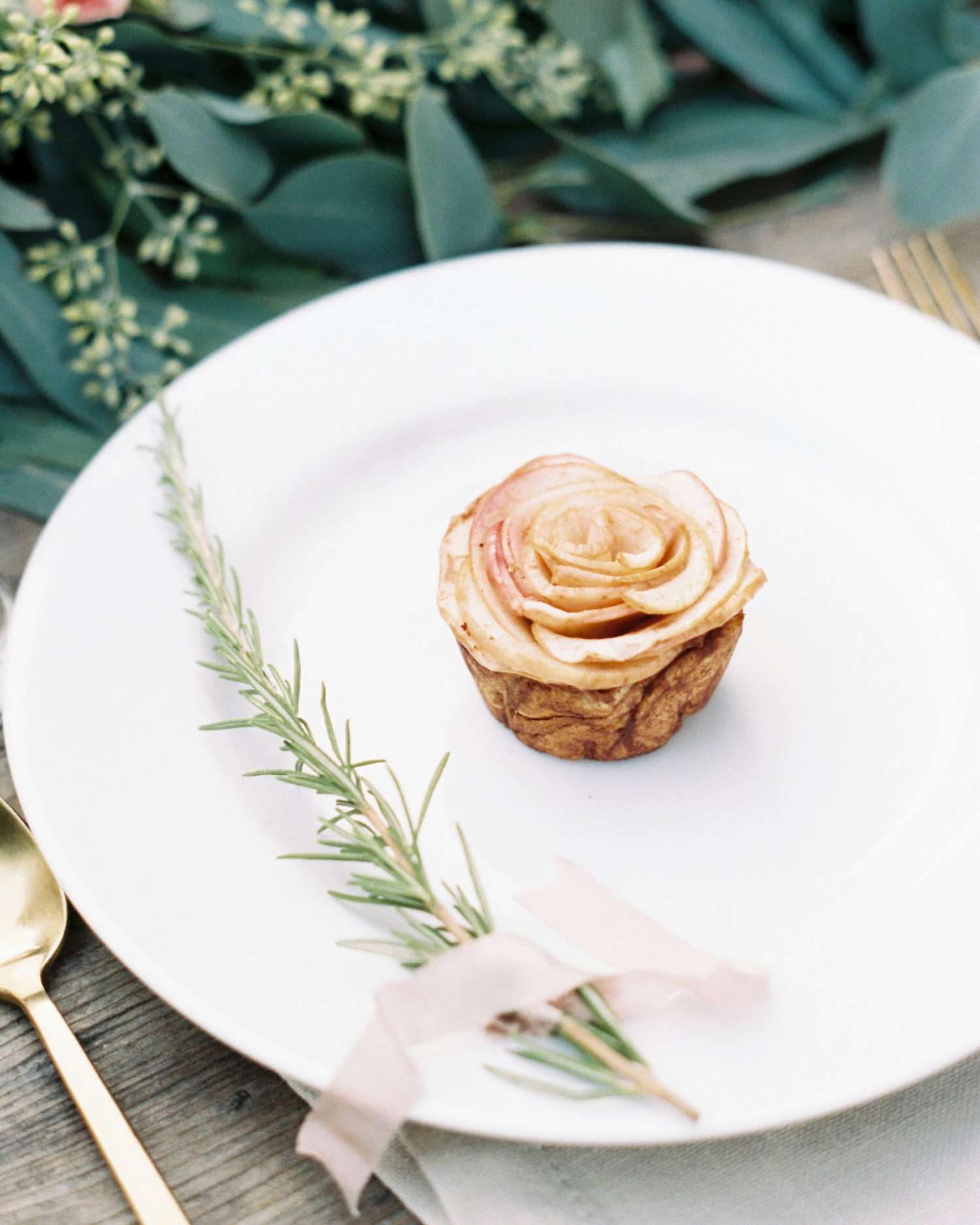 single dessert of white plate with greenery garnish and pink ribbon