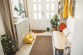 A home entryway with a bench potted plants and a coat rack