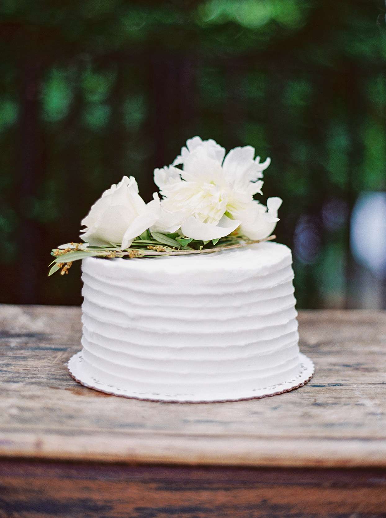 simple white wedding cake with florals on wooden table