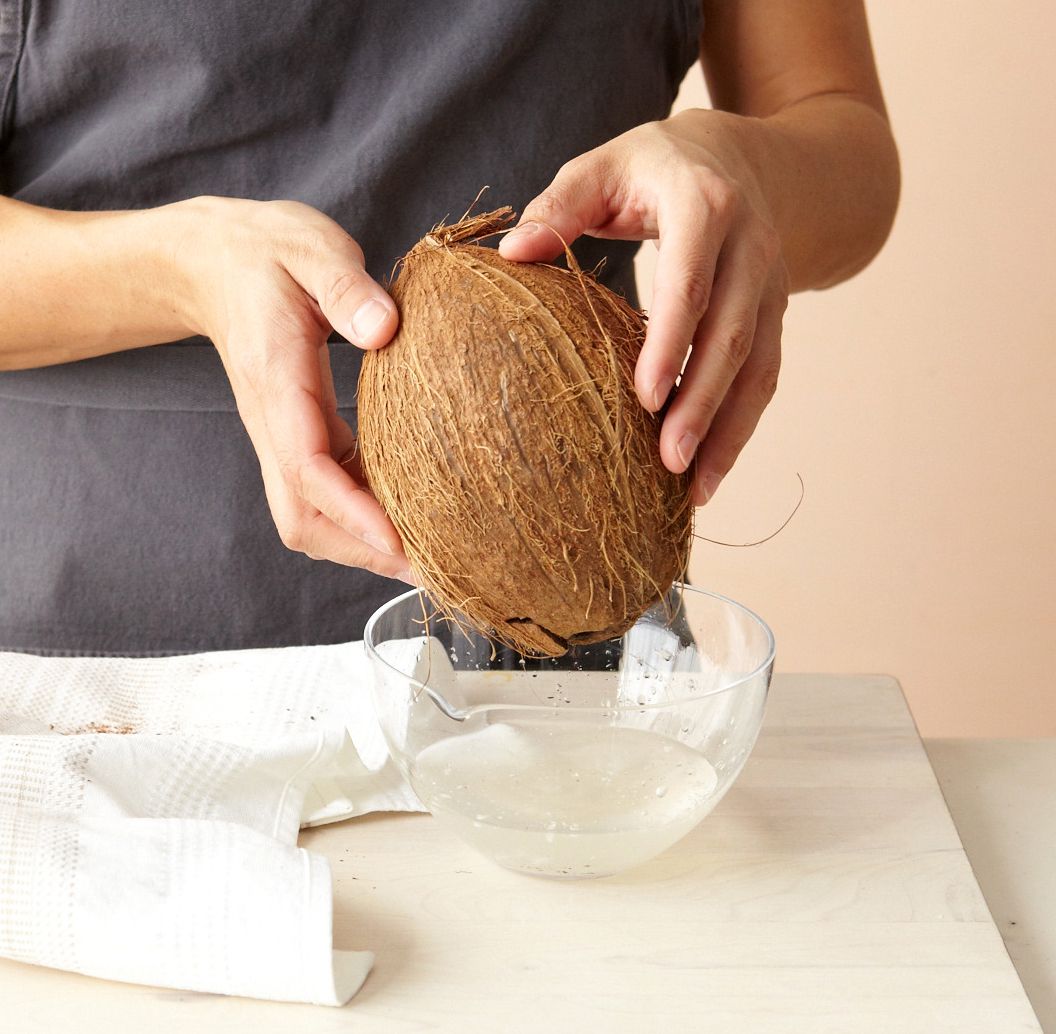 hands holding coconut bowl water