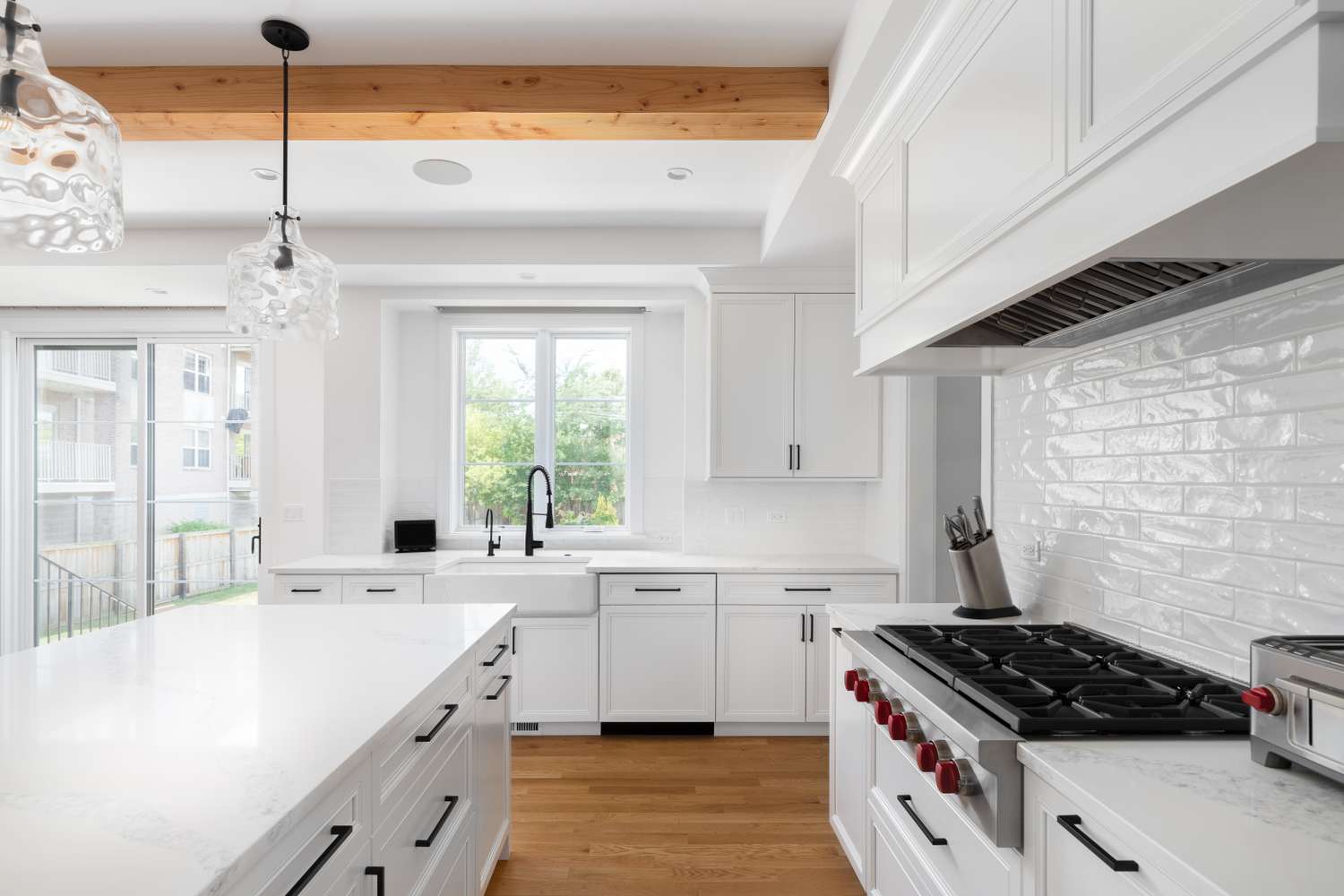 Modern kitchen with white cabinets island gas stove and pendant lighting