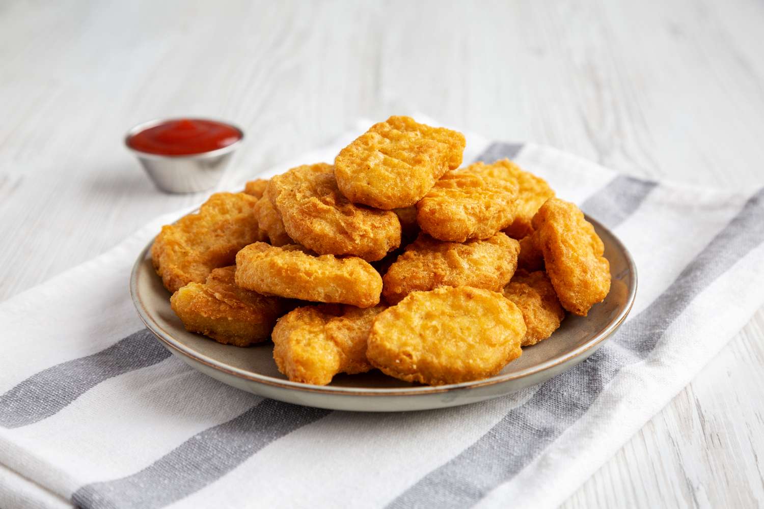 Plate of chicken nuggets with a small cup of ketchup on the side