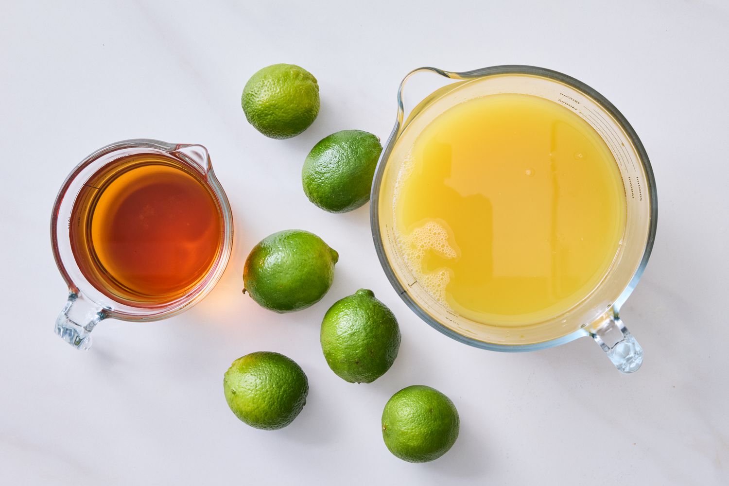 Ingredients for making a pineapple rum cocktail including limes pineapple juice and rum