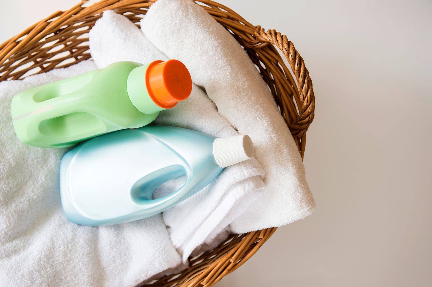 wicker basket filled with white towels and laundry detergent bottles