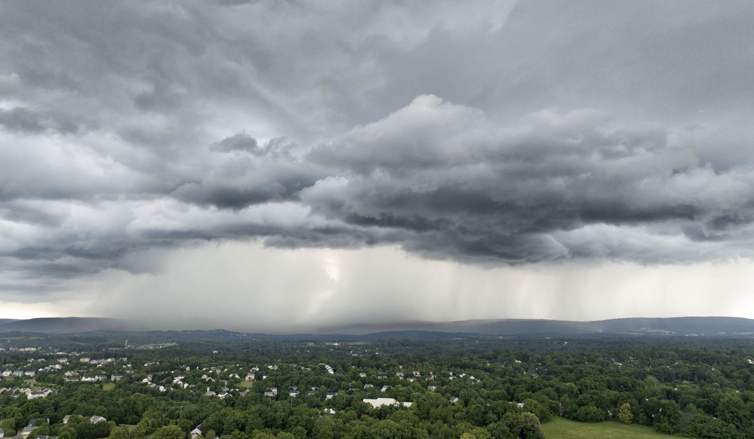 Cloudy sky with rain over a green landscape
