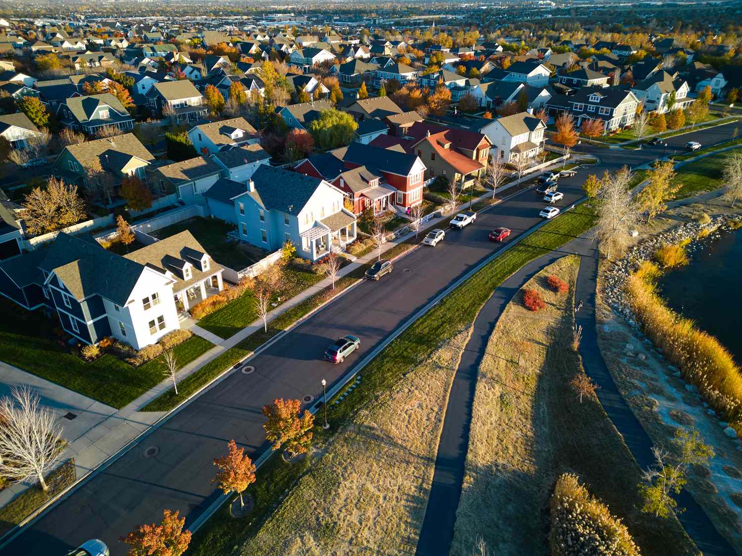 A residential neighborhood with houses roads and a visible water body or park on the side