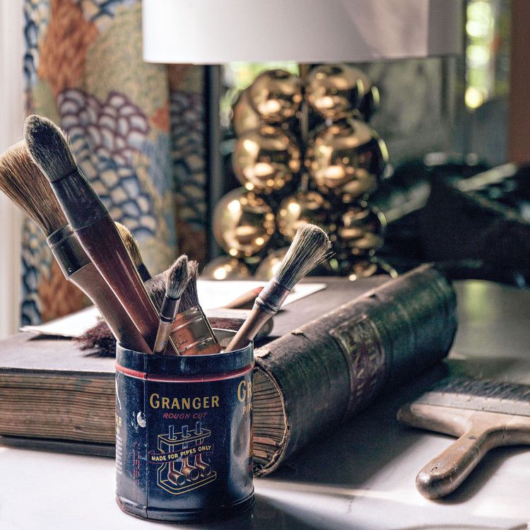 antique book and vintage can filled with paintbrushes