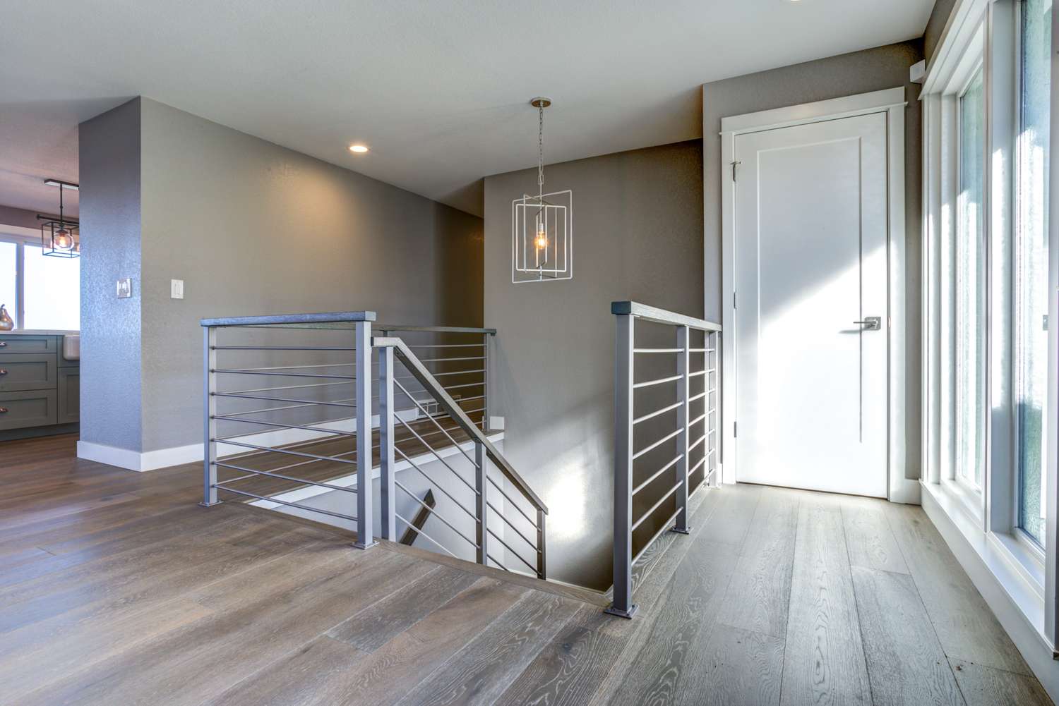 Spacious upstairs landing with gray walls and staircase.