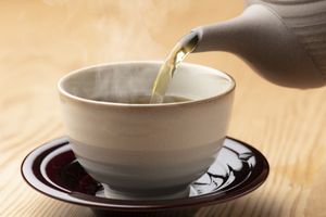 Tea being poured into a cup on a saucer