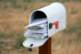 An open mailbox filled with a pile of letters and envelopes