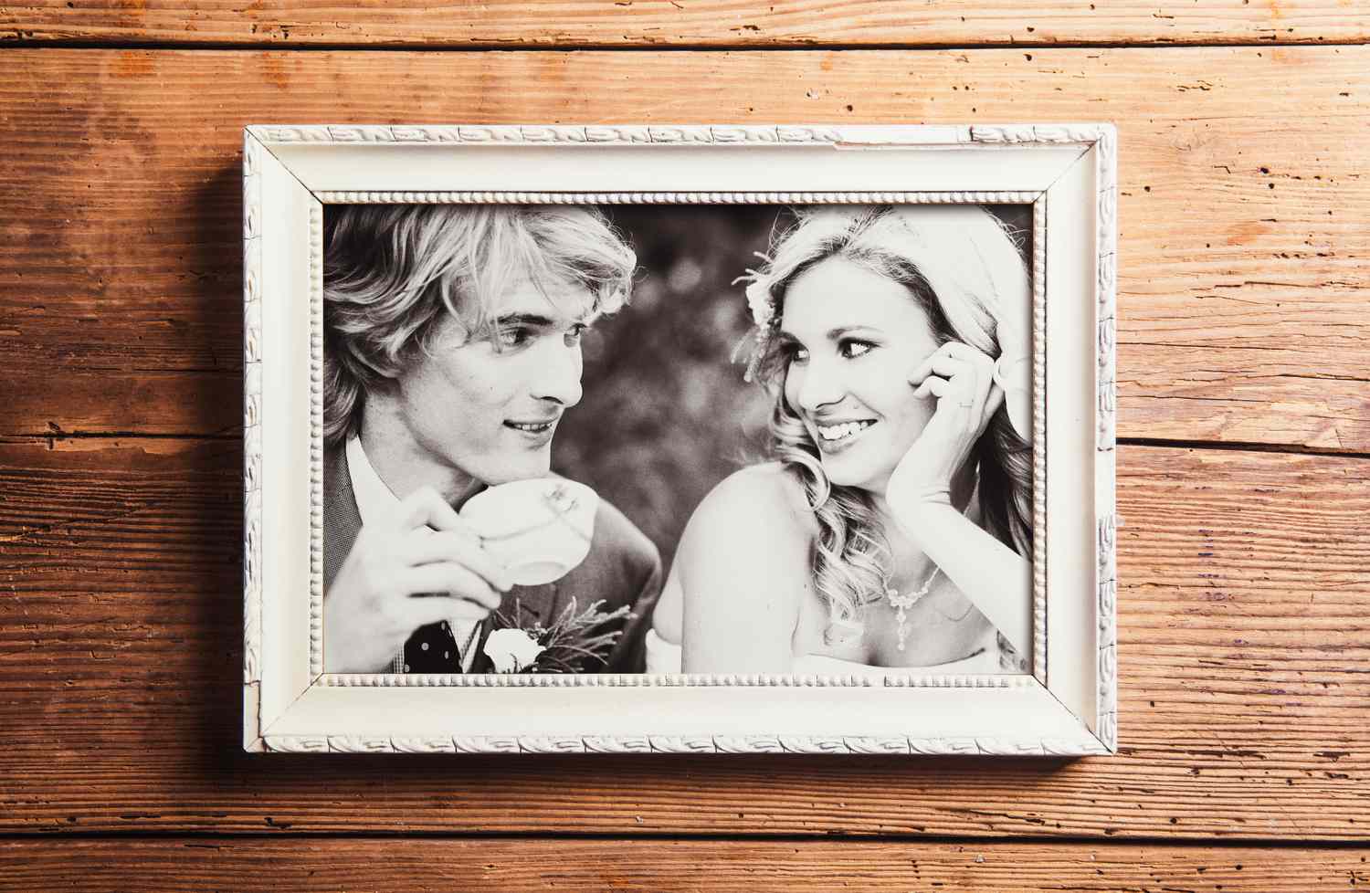 A framed photograph of a man and a woman smiling at each other on a wooden surface