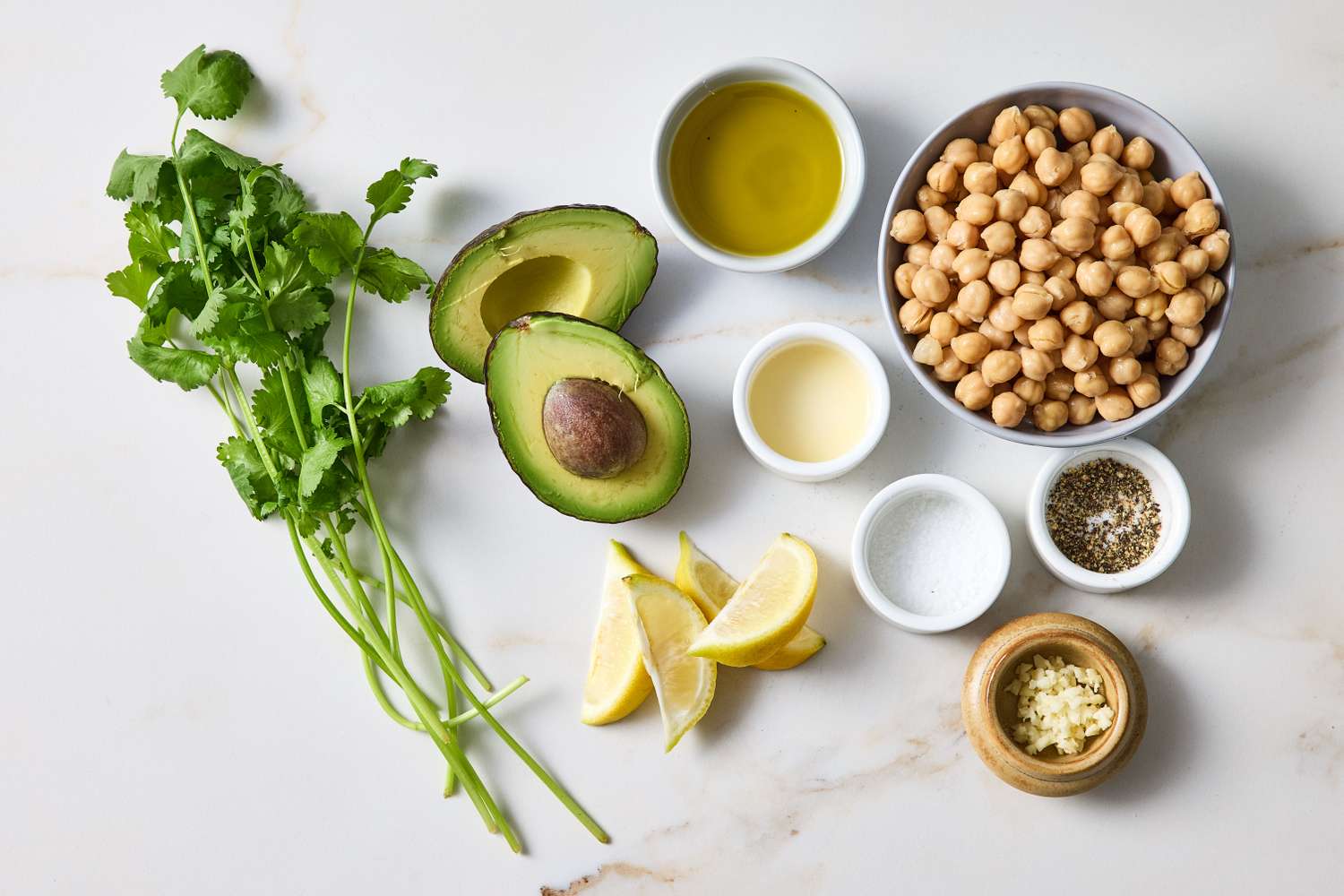 Ingredients for guacamole hummus including chickpeas avocado garlic lemon olive oil salt and pepper