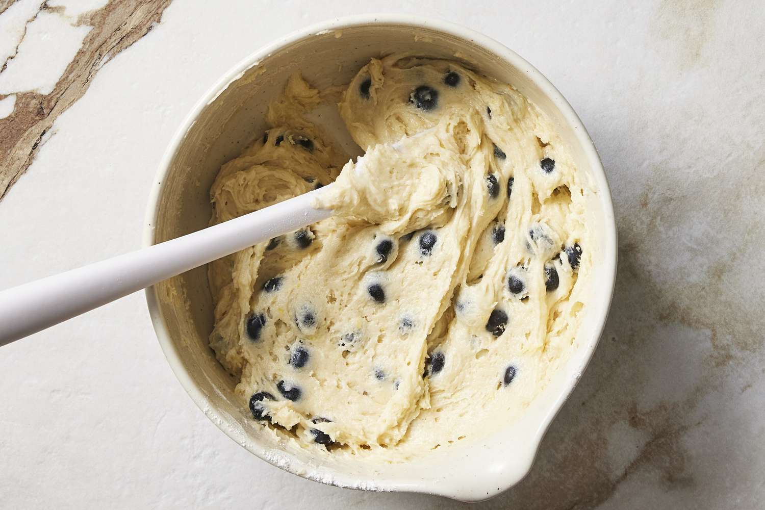 Blueberry cupcake batter in bowl with spoon