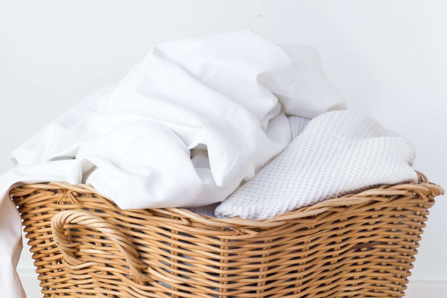 clean white sheets and towels in basket