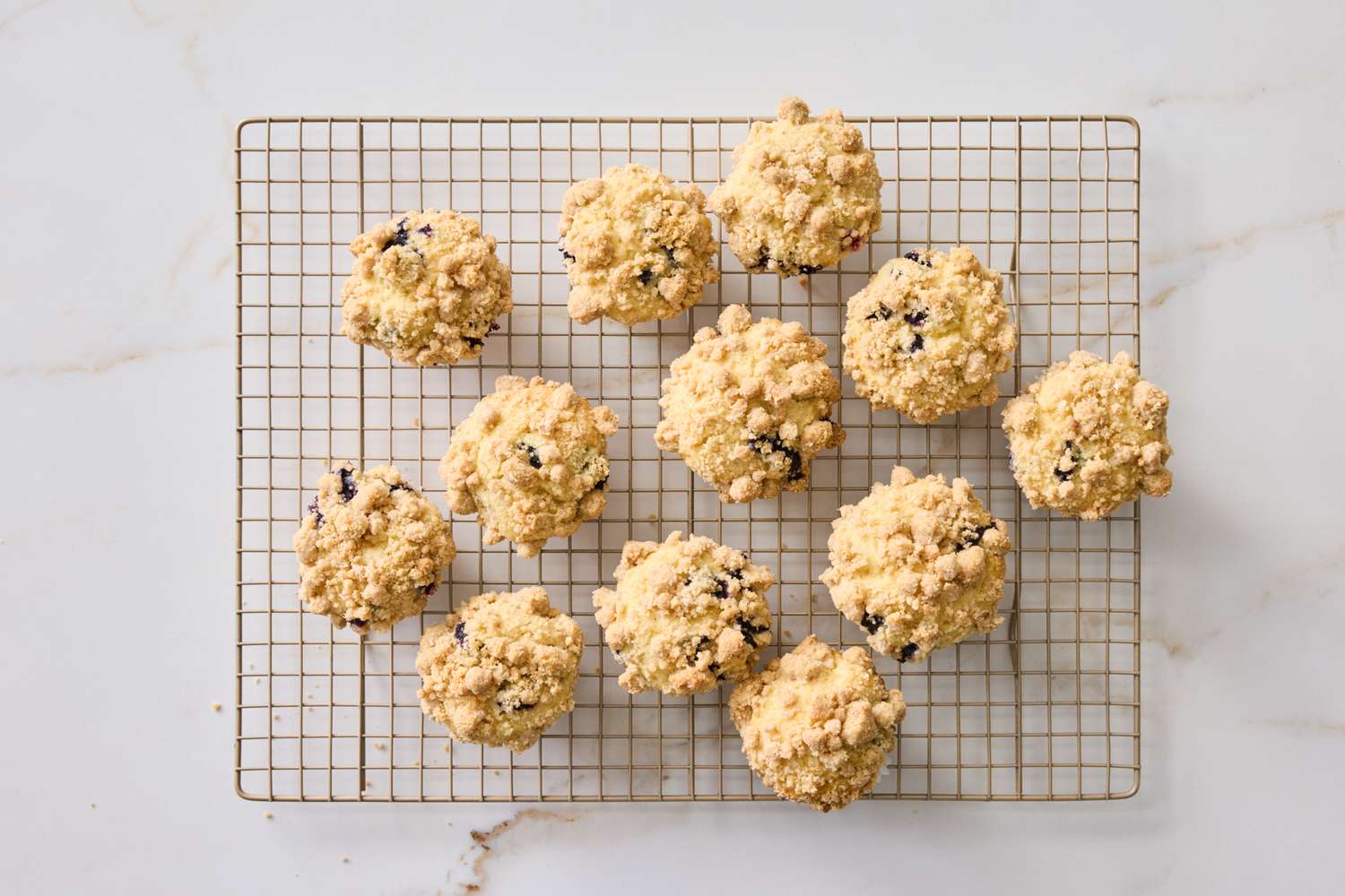 A batch of streuseltopped muffins cooling on a wire rack