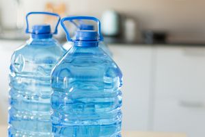 Two large water bottles with handles on a kitchen counter