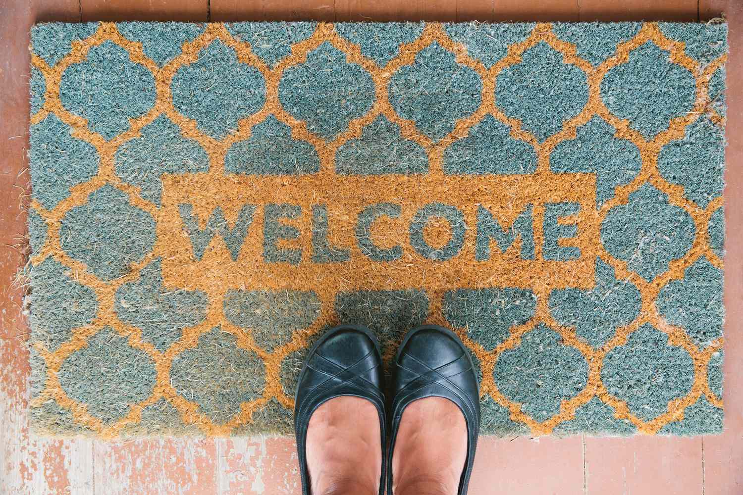 Welcome mat at someones feet showing patterned design and text