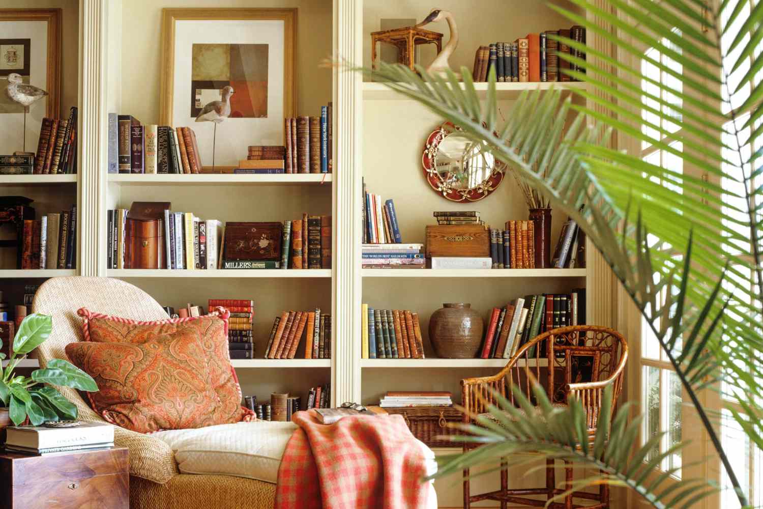 Home library corner with bookshelf and cozy chair with blanket and plant to the side