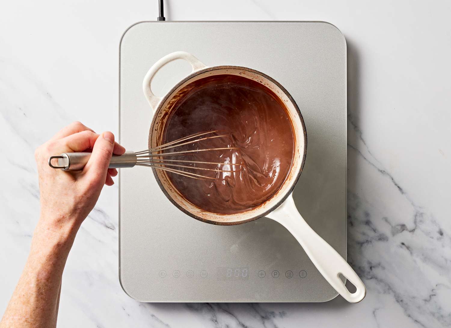 someone stirring chocolate in a pan with a wisk