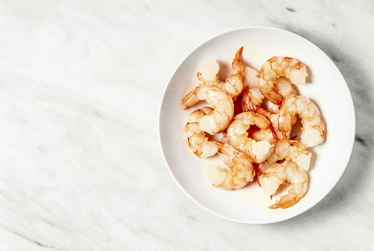 Raw shrimp on a plate on white background