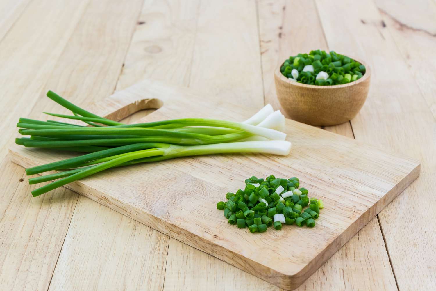 Chopped spring onions on wooden cutting board.