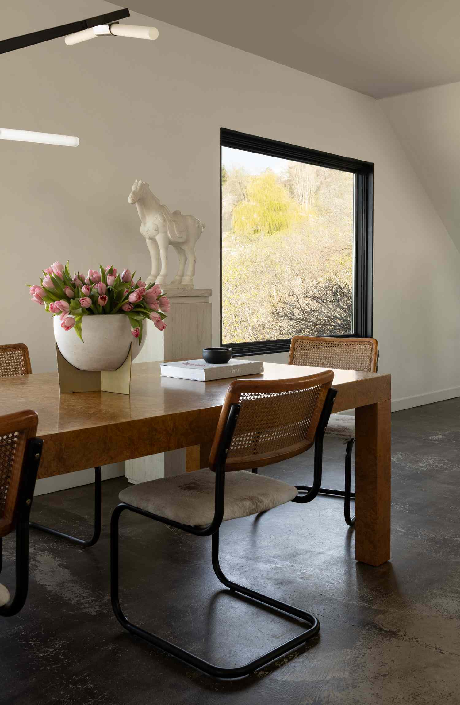 Dining table with chairs flower arrangement and window view