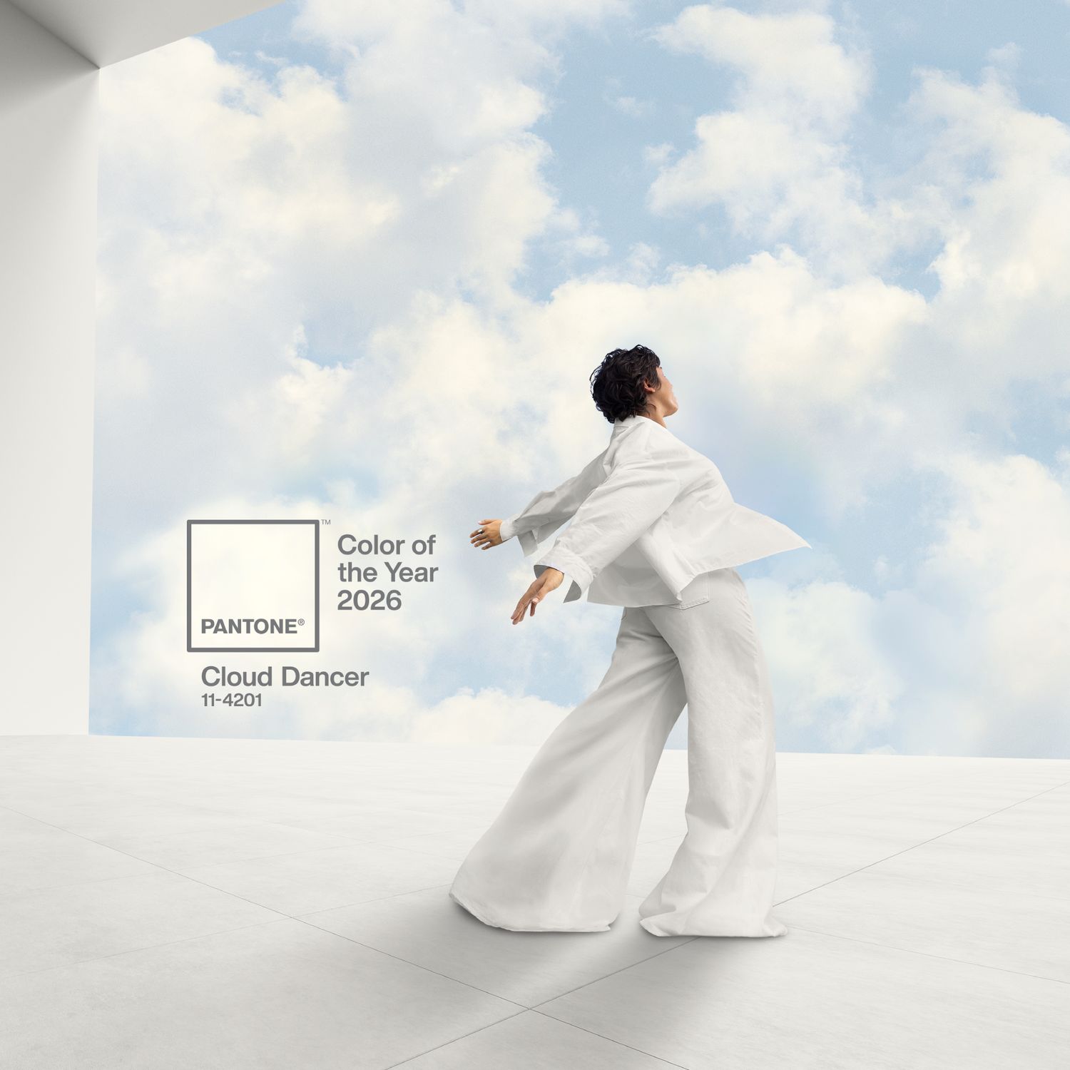 A person in a white outfit poses against a background of a cloudy sky with text indicating Pantones Color of the Year 2026 Cloud Dancer