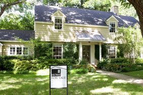 A residential home with a Home For Sale sign in the front yard