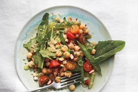 Salad with chickpeas greens and cherry tomatoes on a plate with a fork