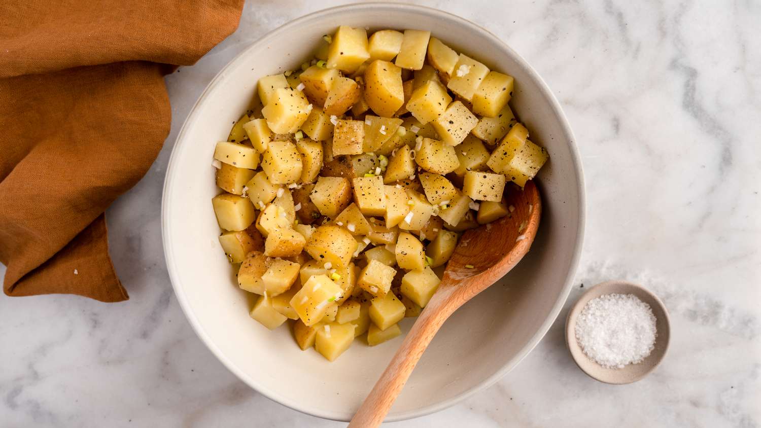 potatoes being mixed with vinegar in bowl