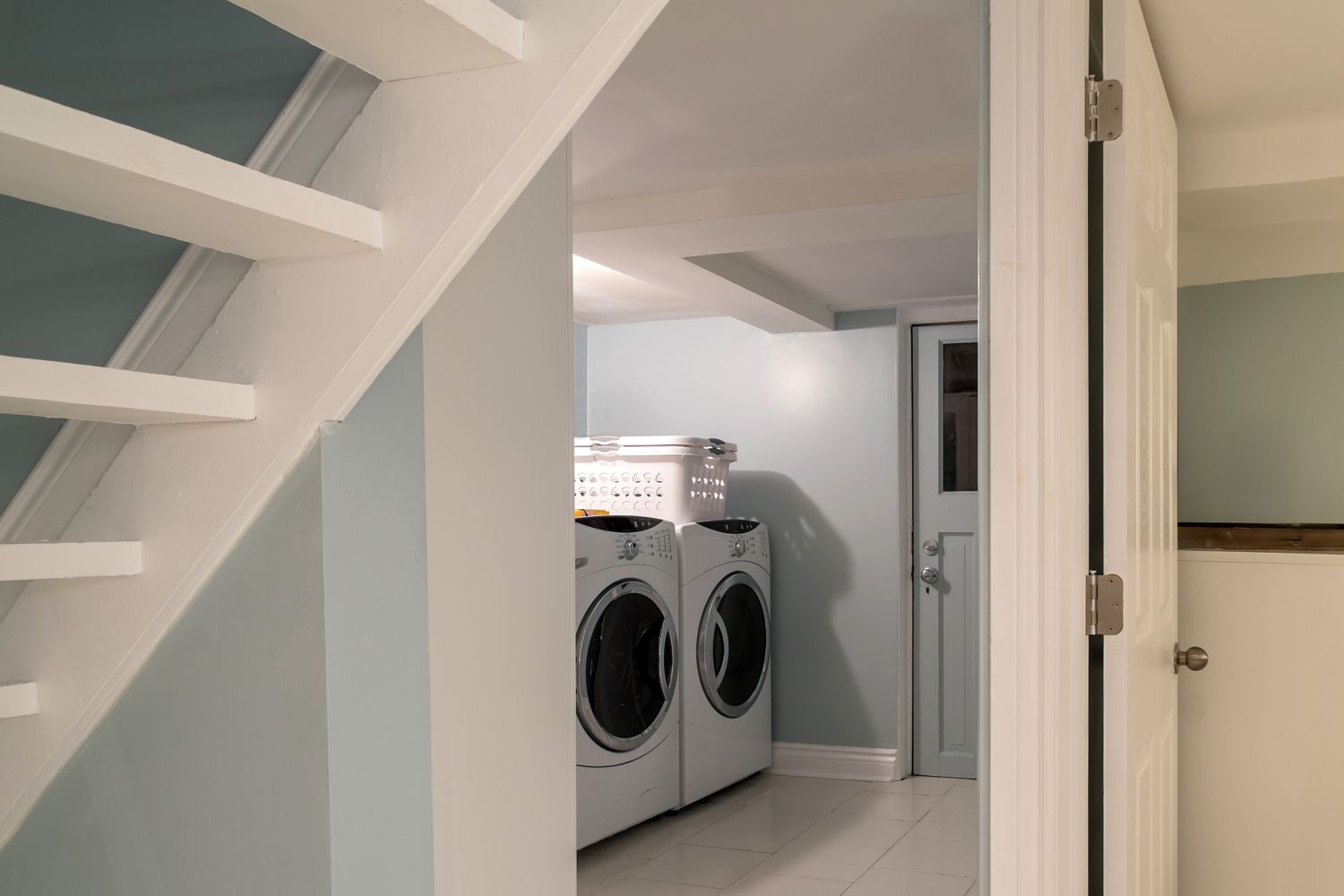A basement laundry room with a washer dryer and staircase visible