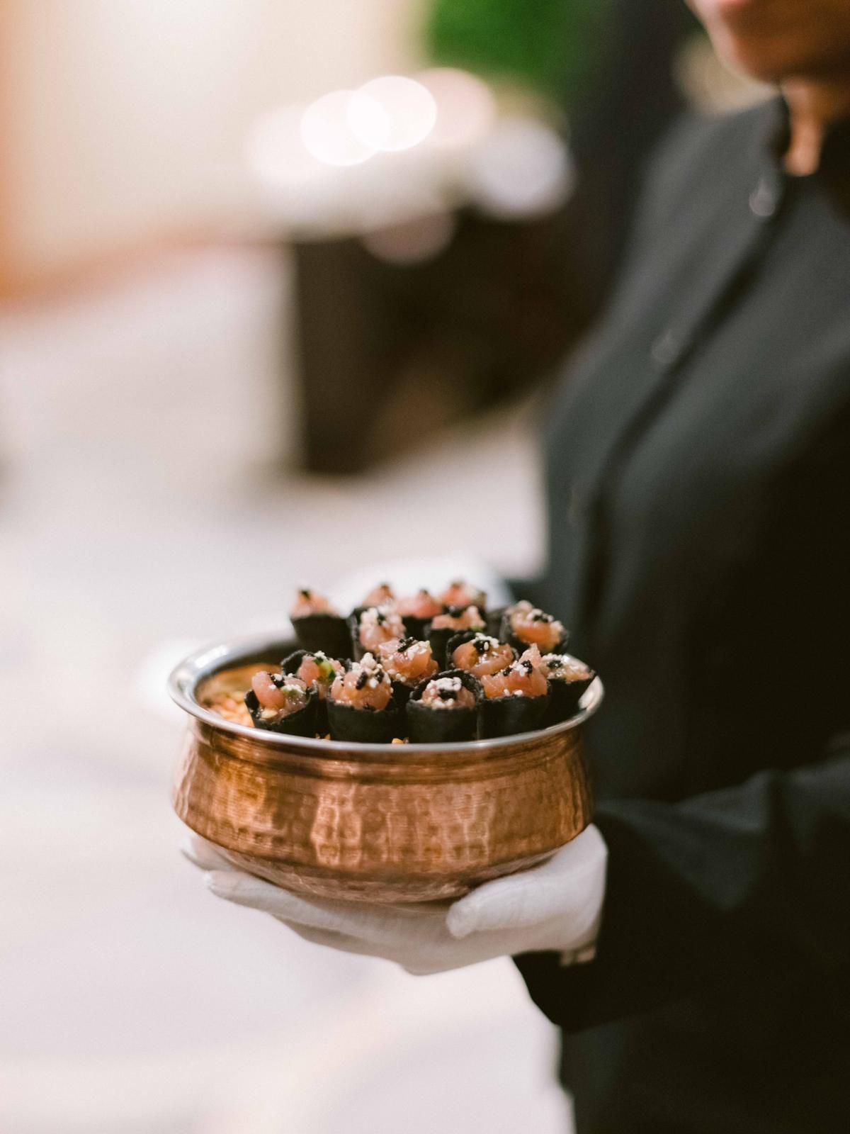 server holding copper dish of wedding appetizers