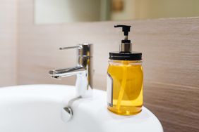 Close-up view of a bottle of yellow hand soap next to a bathroom faucet