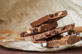 Stack of chocolate bark with nuts and raisins on parchment paper