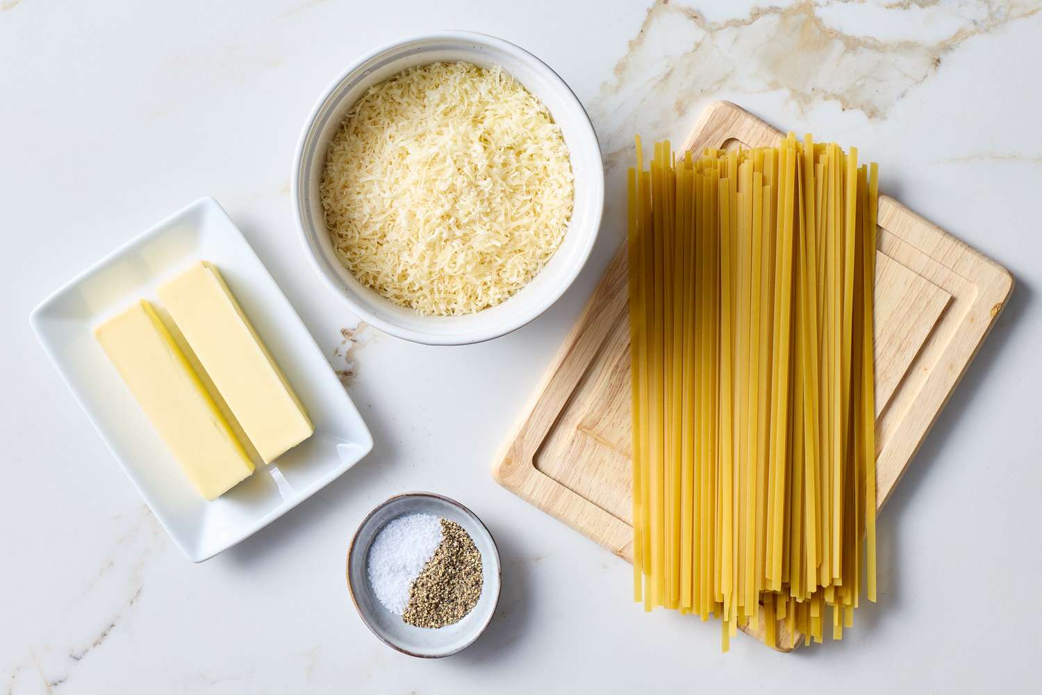 Ingredients for fettuccine Alfredo including butter grated cheese fettuccine pasta salt and pepper