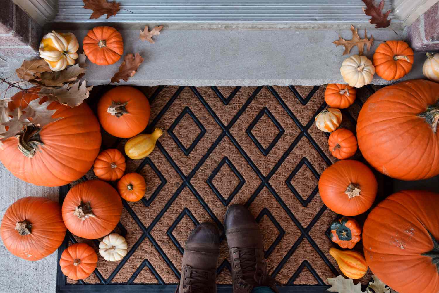 Looking down at front porch door mat decorated with pumpkins and gourds