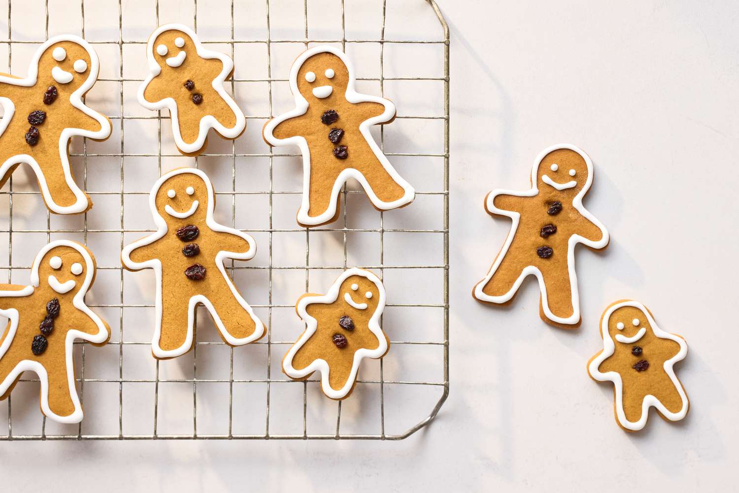 Gingerbread men cookies with icing and raisin decorations on a cooling rack