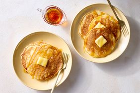 Plates of pancakes served with butter and syrup a small pitcher of syrup beside them