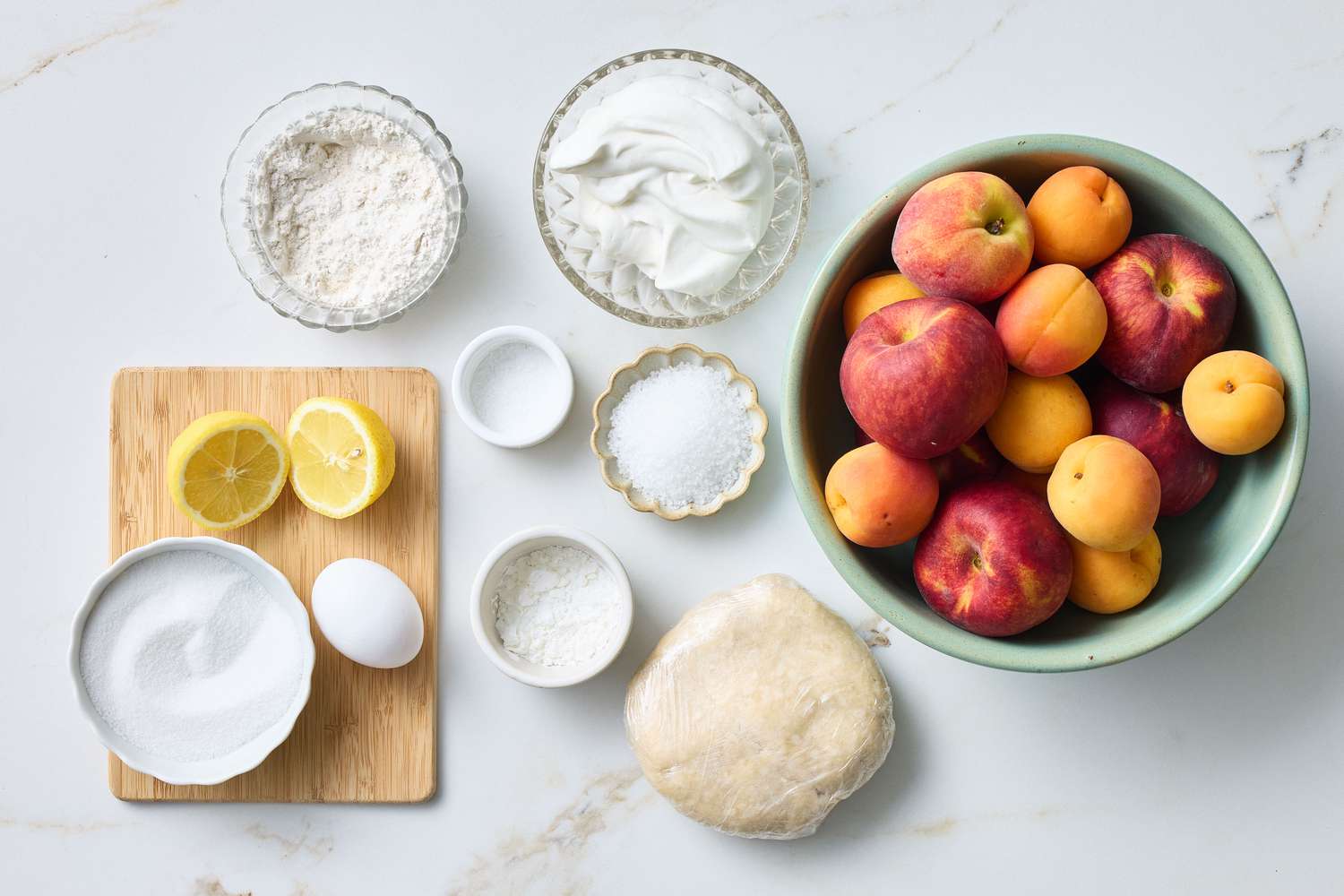 Ingredients for making a stone fruit galette, including fruit, pastry dough, and baking essentials