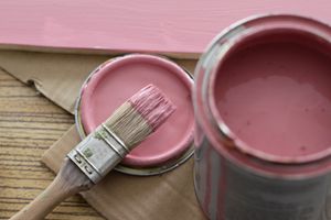 open can of pink paint with brush