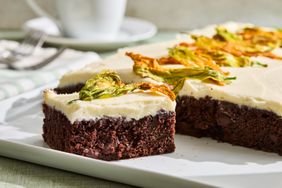 Chocolate zucchini sheet cake with cream cheese frosting and garnished with zucchini flowers one slice removed
