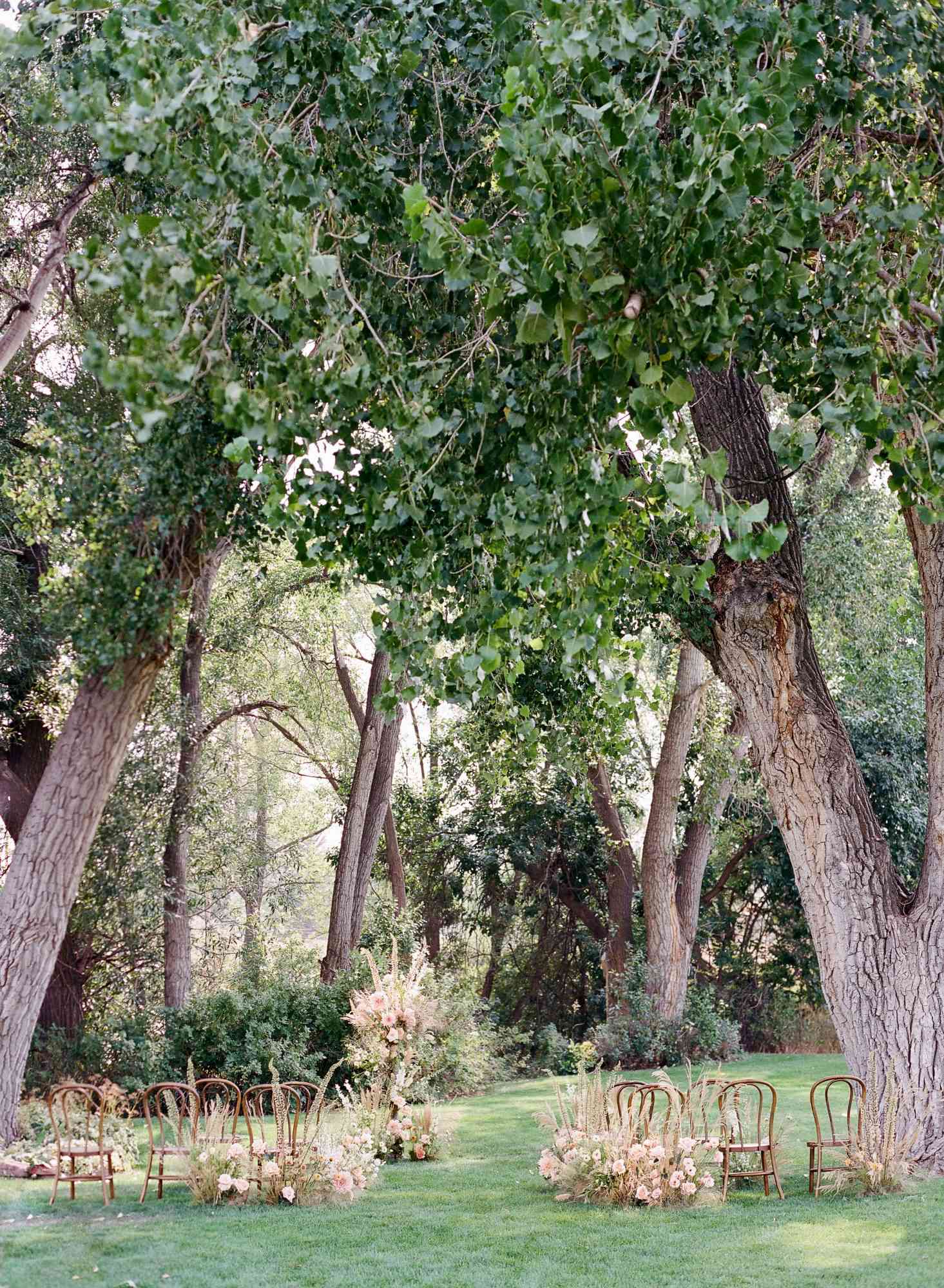 outdoor ceremony space with wooden chairs and floral arch