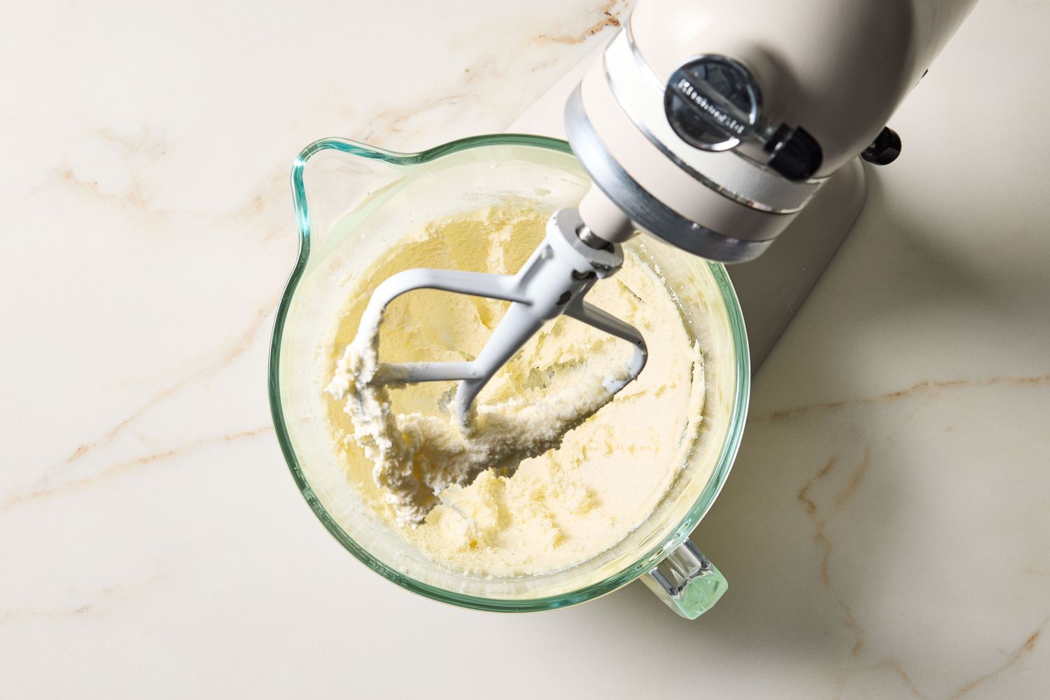 A stand mixer with a bowl containing creamed butter and sugar