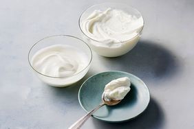 Two bowls of yogurt next to a spoon with yogurt on a small plate