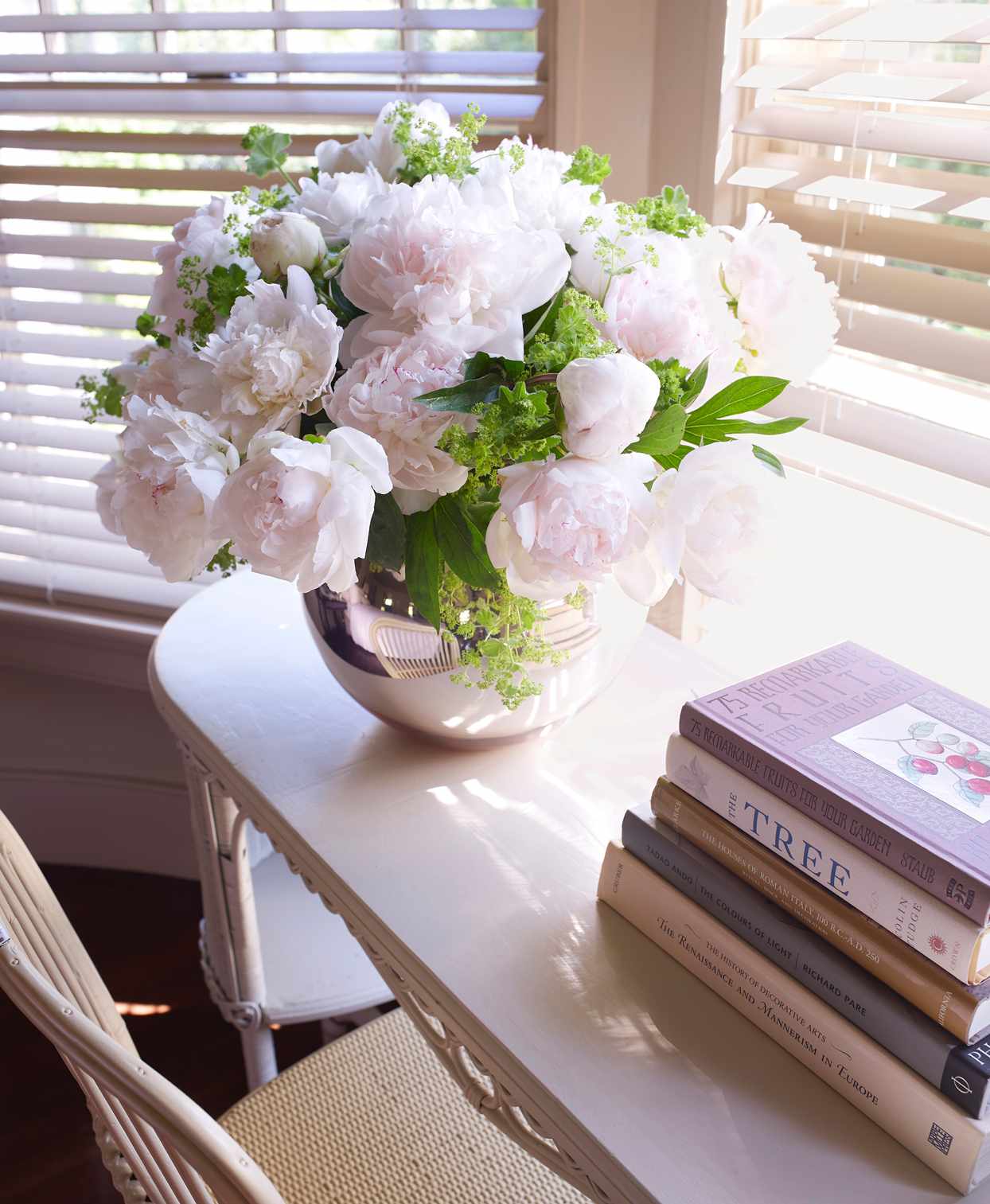 peonies from garden atop wicker writing desk