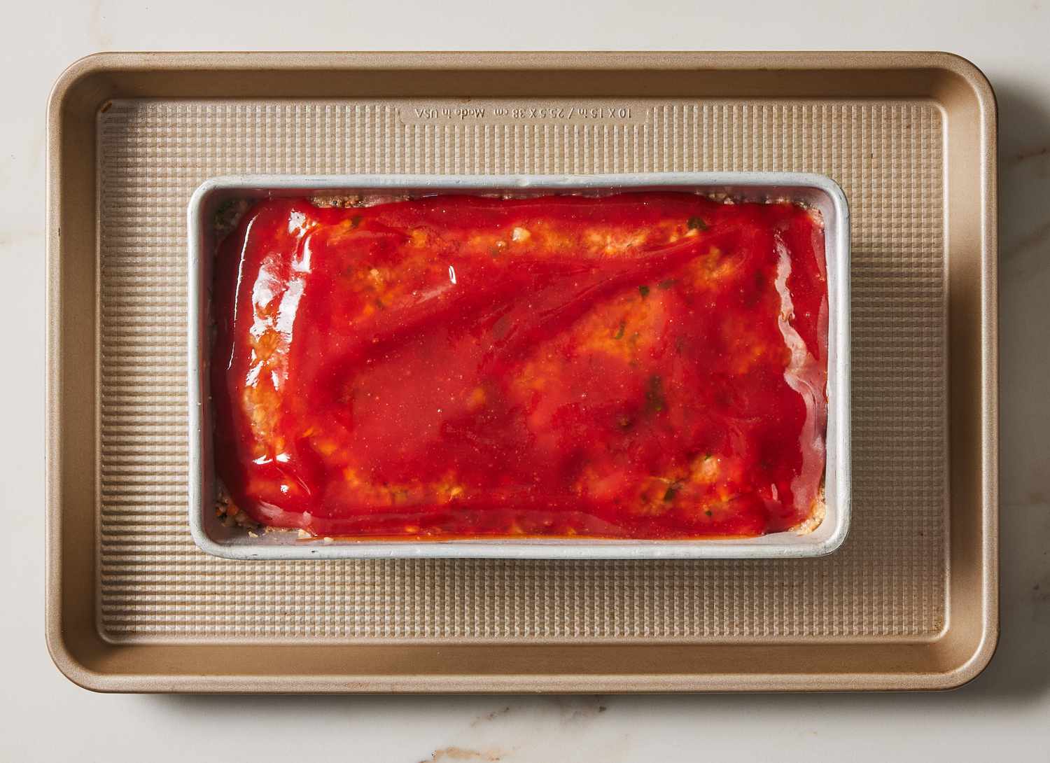 unbaked meatloaf in a pan resting on a baking sheet
