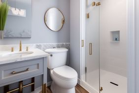 Bathroom with a sink toilet round mirror and glass shower enclosure