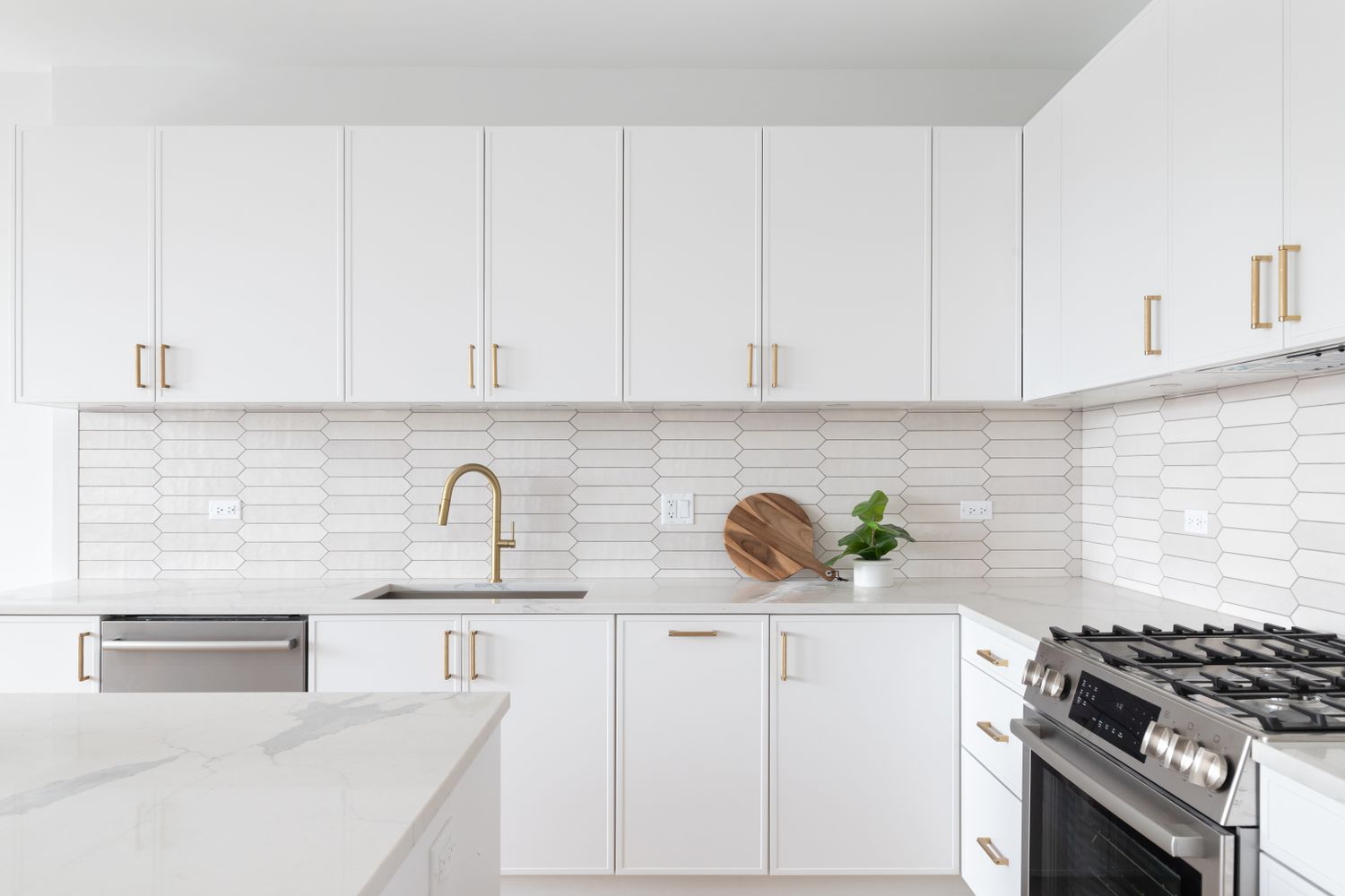 Modern kitchen with laminate cabinets a gas stove a marble countertop and a decorative backsplash