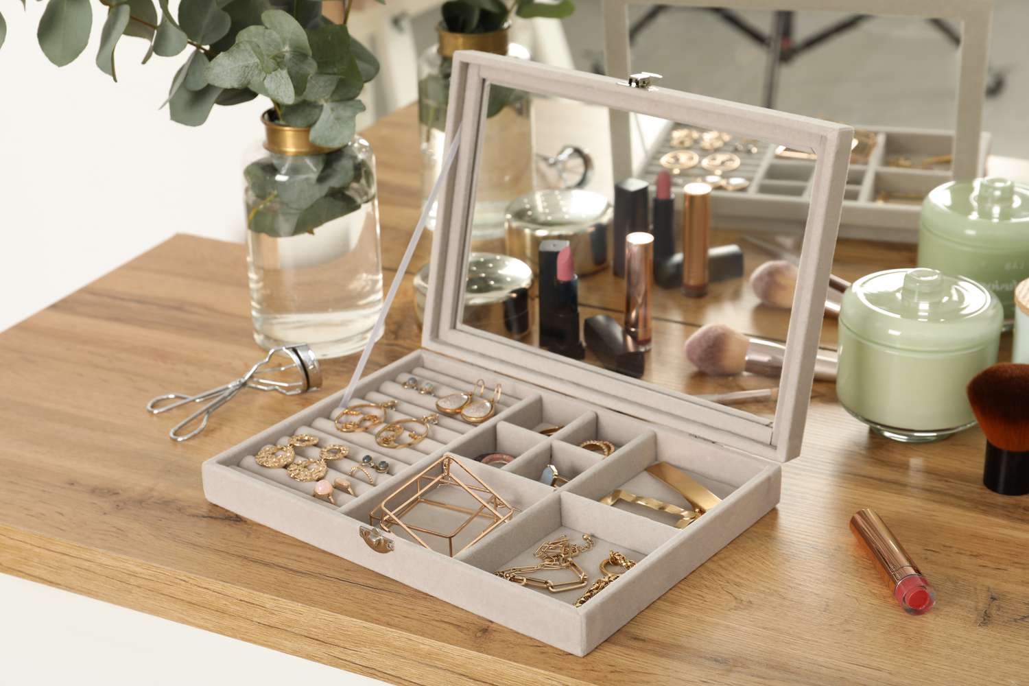 Stackable jewelry box with cosmetics and candles on wooden table. 