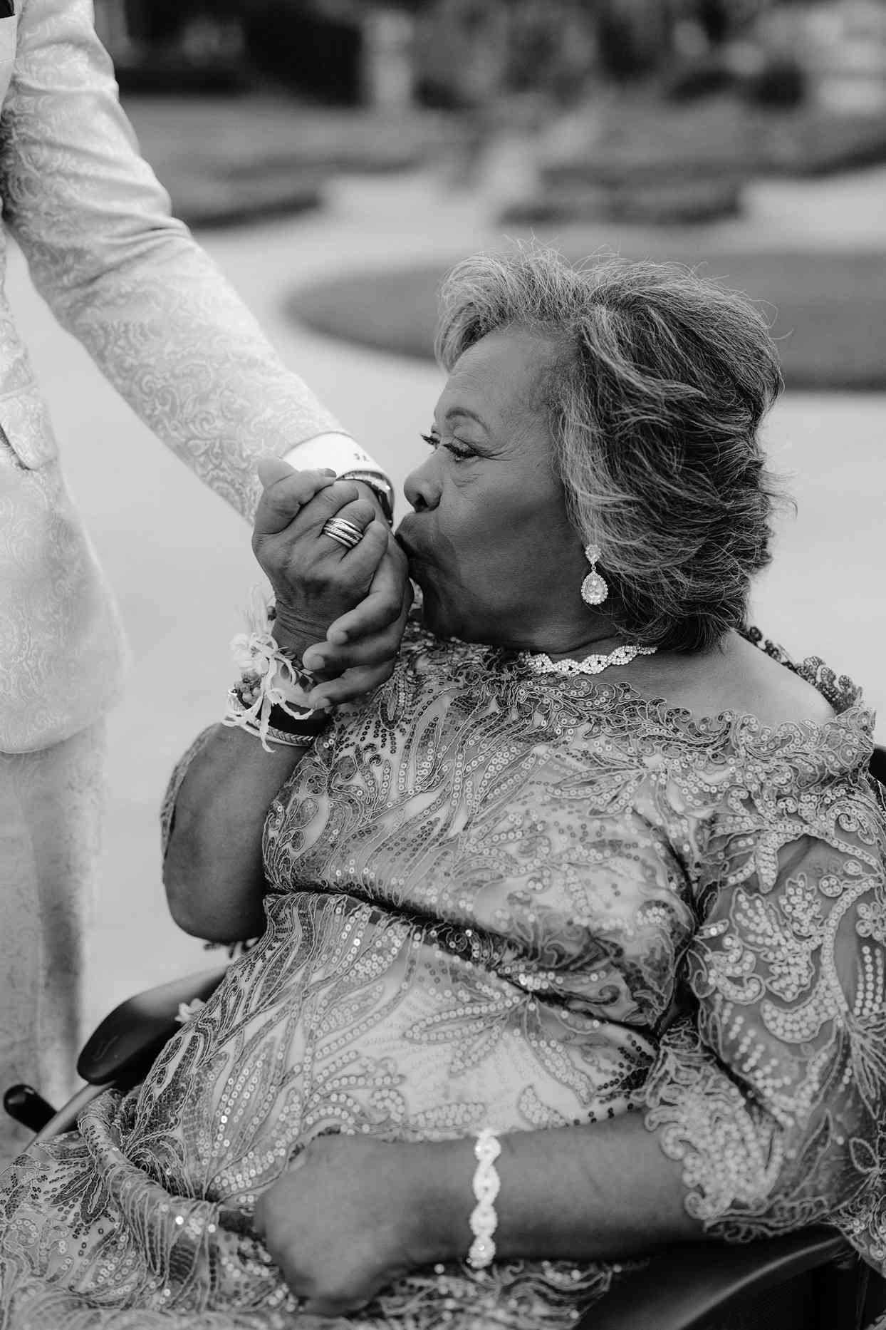 mother of the groom in sequined dress kissing groom's hand